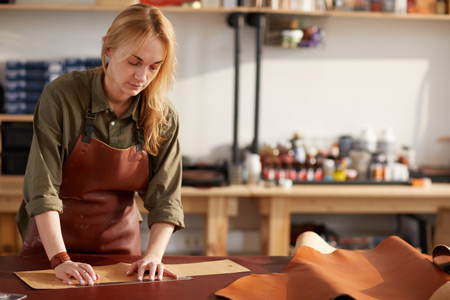 A female small business owner works in her custom leather shop
